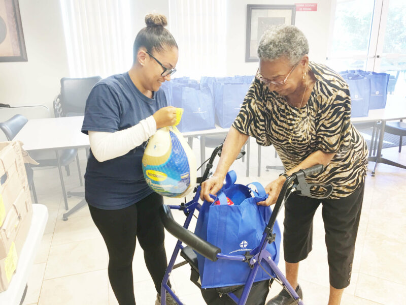 Younger nurse giving a turkey to an older woman.