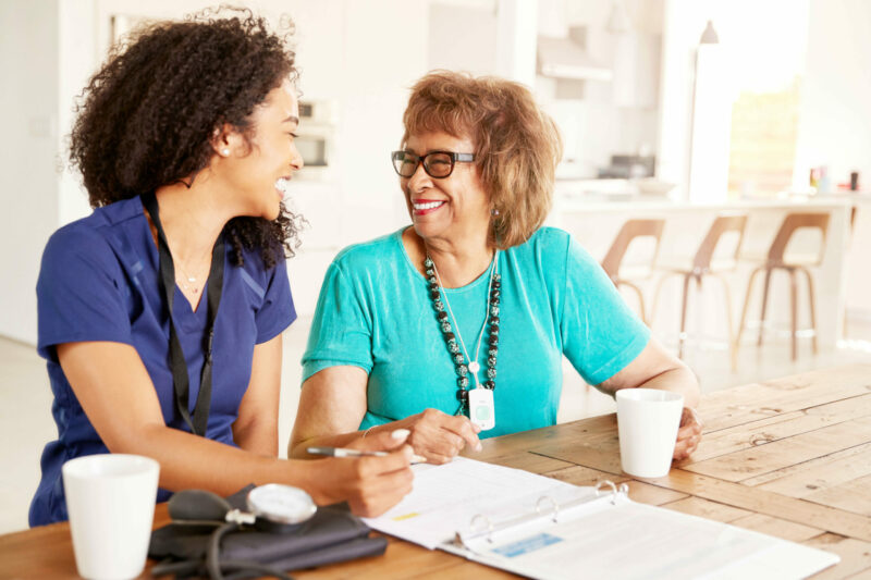 Aide helping a middle aged woman fill out a form.