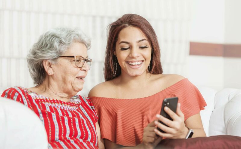 Younger woman showing an older woman her phone